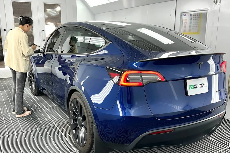EV Central Service technician inspecting a blue Tesla Model Y in paint booth for free collision estimate San Francisco