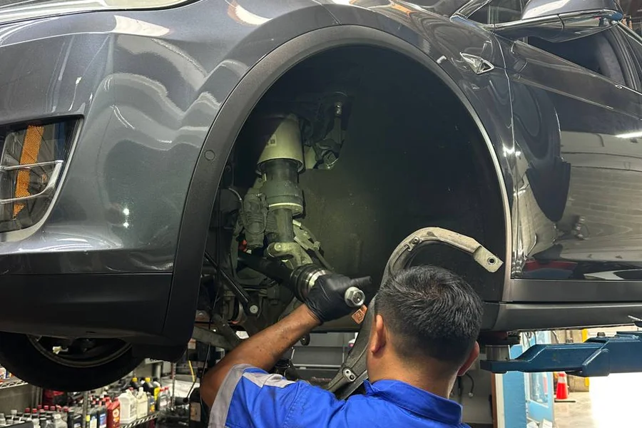 Mechanic repairing Tesla axle and CV joint on lift at EV Central Service San Francisco