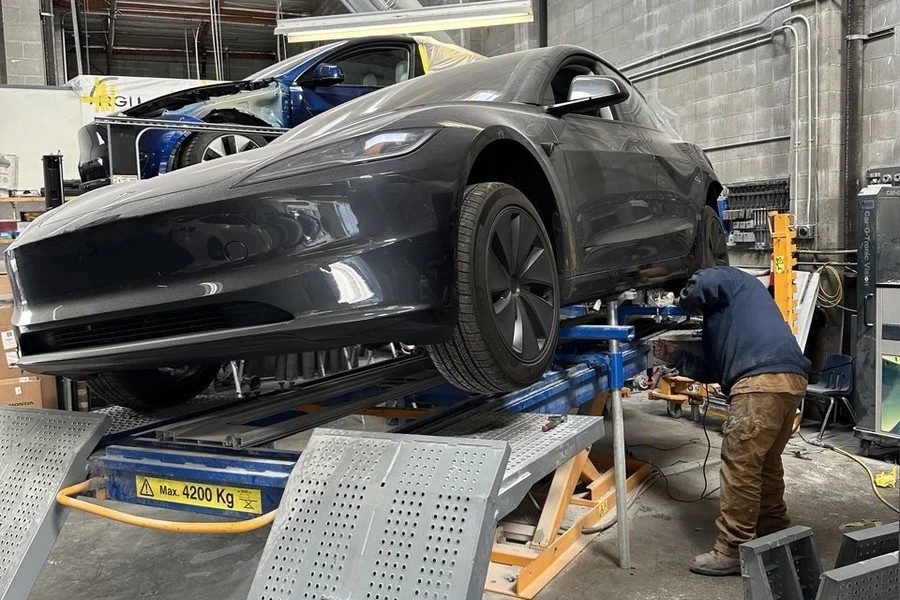 Dark grey Tesla Model 3 Highland on frame straightening lift at EV Central Service Tesla body shop near Sunset District San Francisco