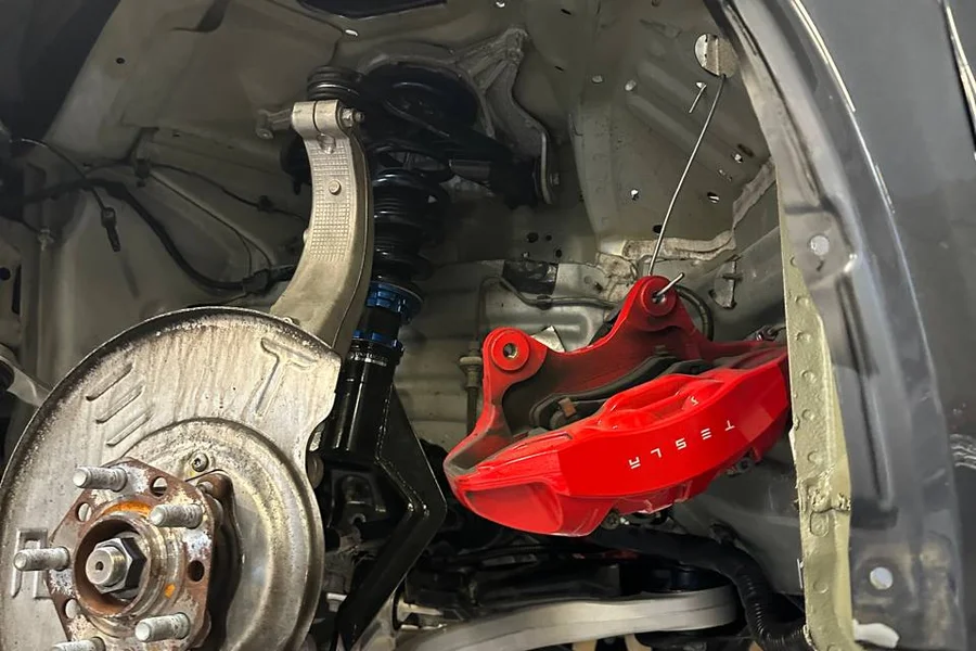 Tesla red brake caliper and worn rotor with wheel removed at EV Central Service San Francisco
