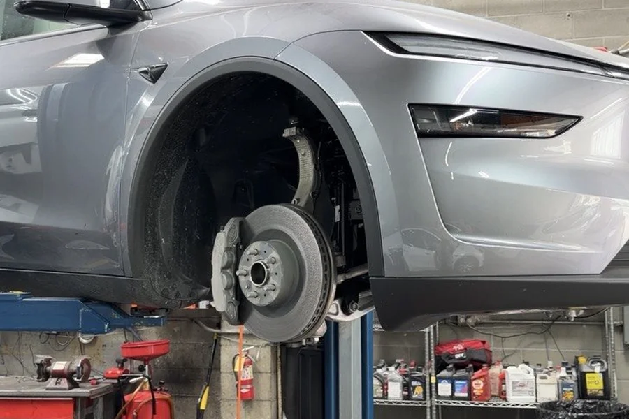 Grey Tesla Model Y on lift with brake rotor exposed for suspension repair at EV Central Service near Burlingame
