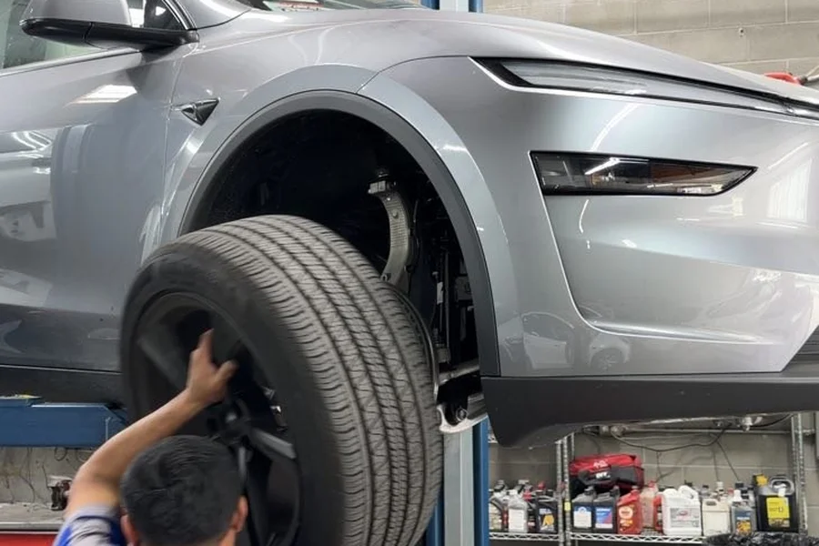 Technician removing Tesla Model Y tire for suspension repair at EV Central Service collision repair shop near Oakland Bay Area