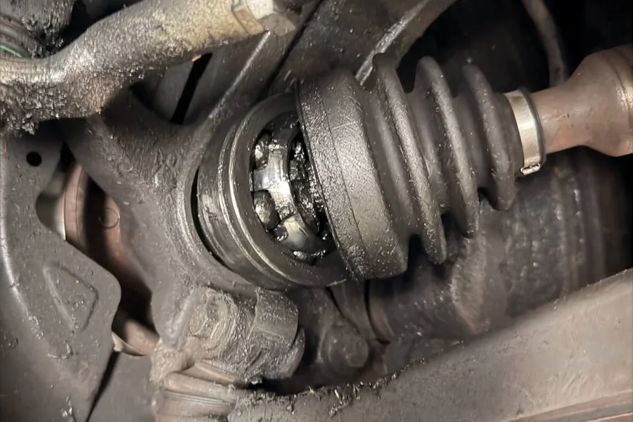 Close-up of worn Tesla CV joint with torn axle boot exposing grease at EV Central Service San Francisco