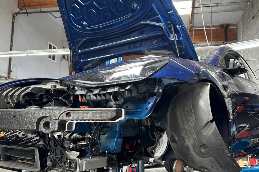 Blue Tesla with front end disassembled showing suspension components at EV Central Service San Francisco