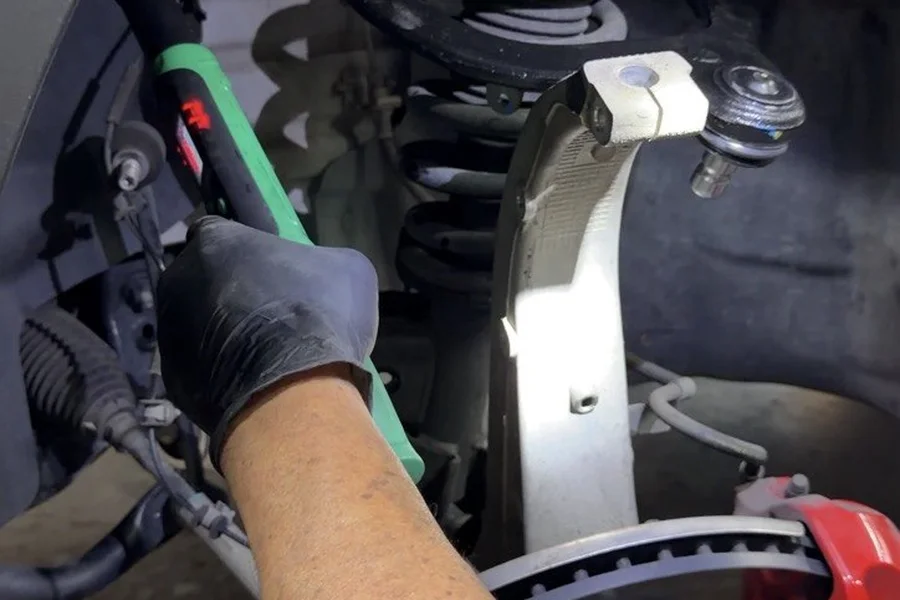 Technician replacing Tesla suspension control arm and brake rotor at EV Central Service mechanical repair Bay Area