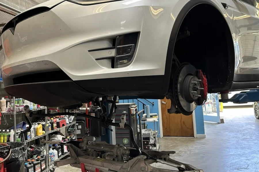 White Tesla Model X with front subframe removed for mechanical repair at EV Central Service South San Francisco Bay Area