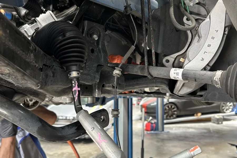 Tesla CV axle and suspension components exposed underneath on lift at EV Central Service mechanical repair near Daly City