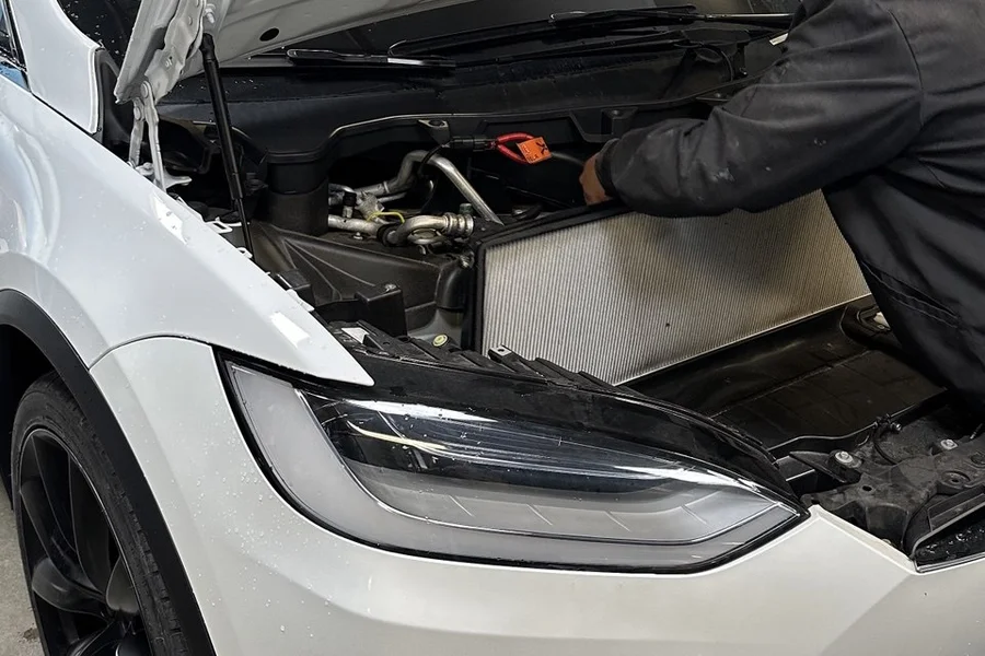 Technician servicing Tesla Model X thermal system with hood open at EV Central Service near San Mateo