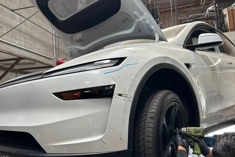 Mechanic removing Tesla Model Y wheel on lift at EV Central Service San Francisco for suspension inspection