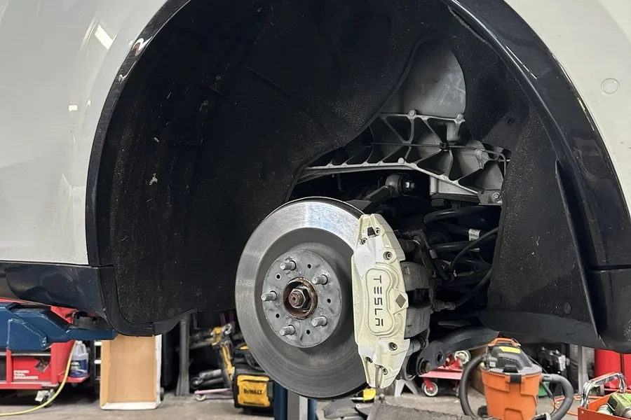 White Tesla brake rotor and Tesla-branded caliper exposed during suspension repair at EV Central Service near Financial District San Francisco