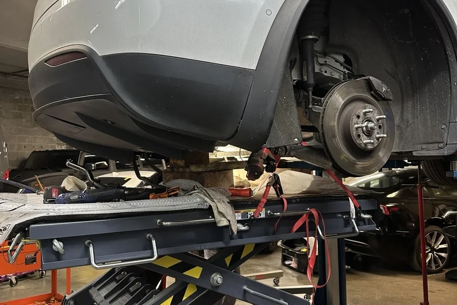 White Tesla Model X on scissor lift for suspension repair at EV Central Service near Mission District San Francisco