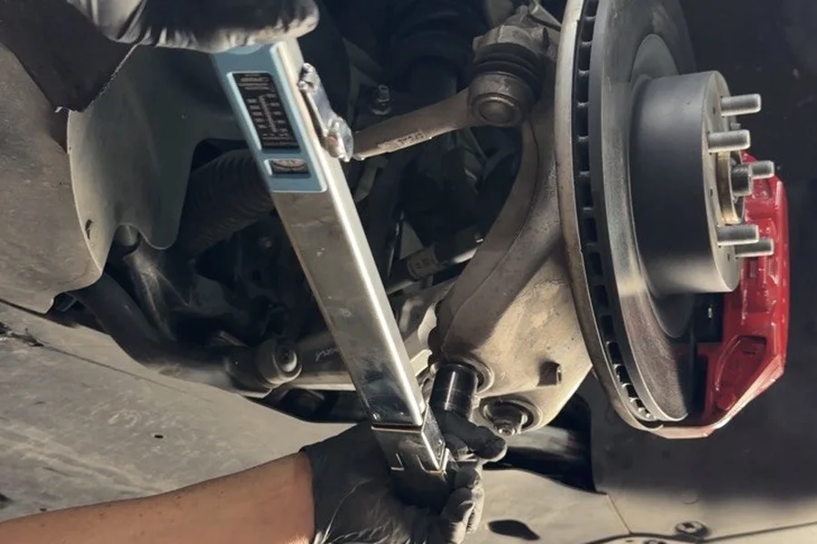 Technician working on Tesla suspension control arm and brake rotor at EV Central Service Bay Area San Francisco