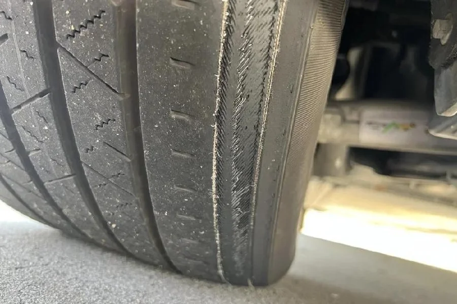 Severely worn Tesla tire tread showing feathering and uneven wear at EV Central Service San Francisco